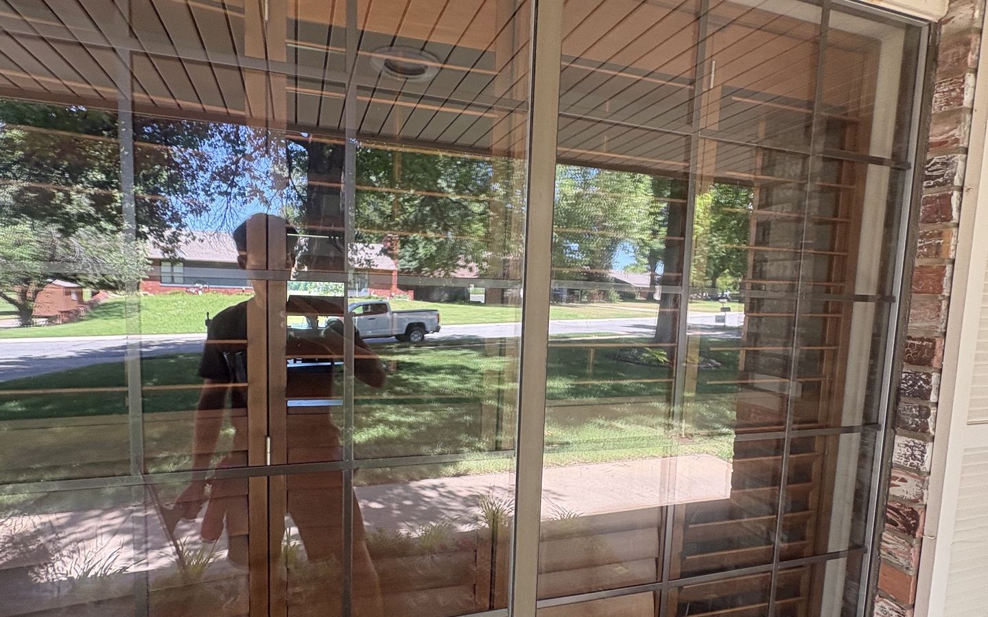 A wall of freshly cleaned patio glass reflecting the trees and street outside
